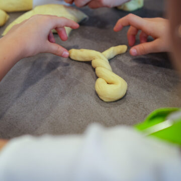 Das große Teigstück zu einer 30 Zentimeter langen Rolle formen. Die Rolle zu Hasen drehen und auf ein Blech mit Backpapier legen.
